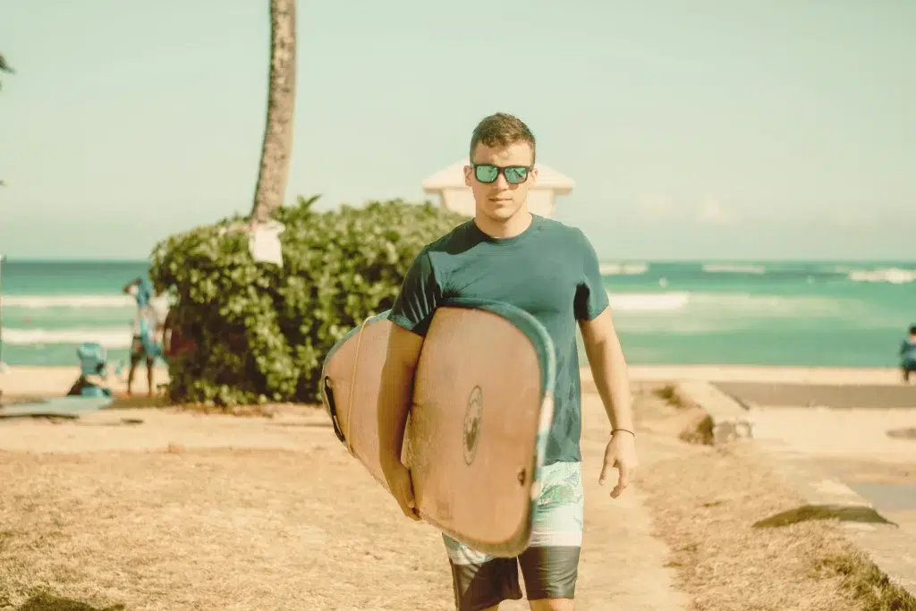 70s Surf Fashion: The Ultimate Retro Coastal Style Guide for Men and Women 4 70s surf fashion men's look with short boardshorts, surf logo tee and aviator sunglasses