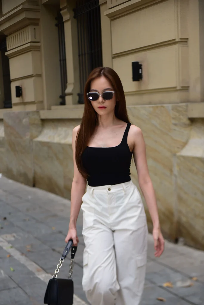 Woman wearing oversized square sunglasses with wide leg linen pants and a white tee