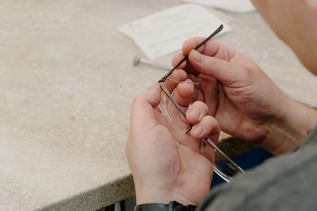 Tightening a loose hinge screw on budget sunglasses with a small eyeglass repair screwdriver