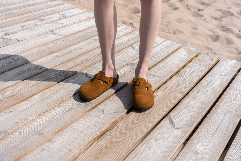 Birkenstock Arizona vs Boston: Which One Fits You Better? 3 Woman wearing Birkenstock Boston clogs with cream socks and straight leg jeans on an autumn street