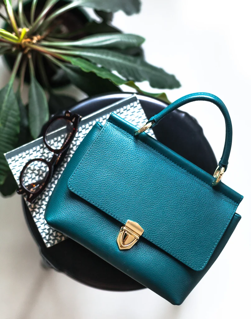 Fashionphile vs The RealReal: Which Pays You More? 1 Leather handbag beside a laptop and notepad while comparing Fashionphile vs The RealReal payouts