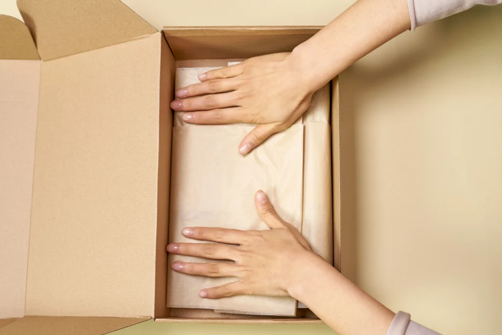 Fashionphile vs The RealReal: Which Pays You More? 3 Packing a designer handbag in a dust bag and shipping box to send to a resale platform