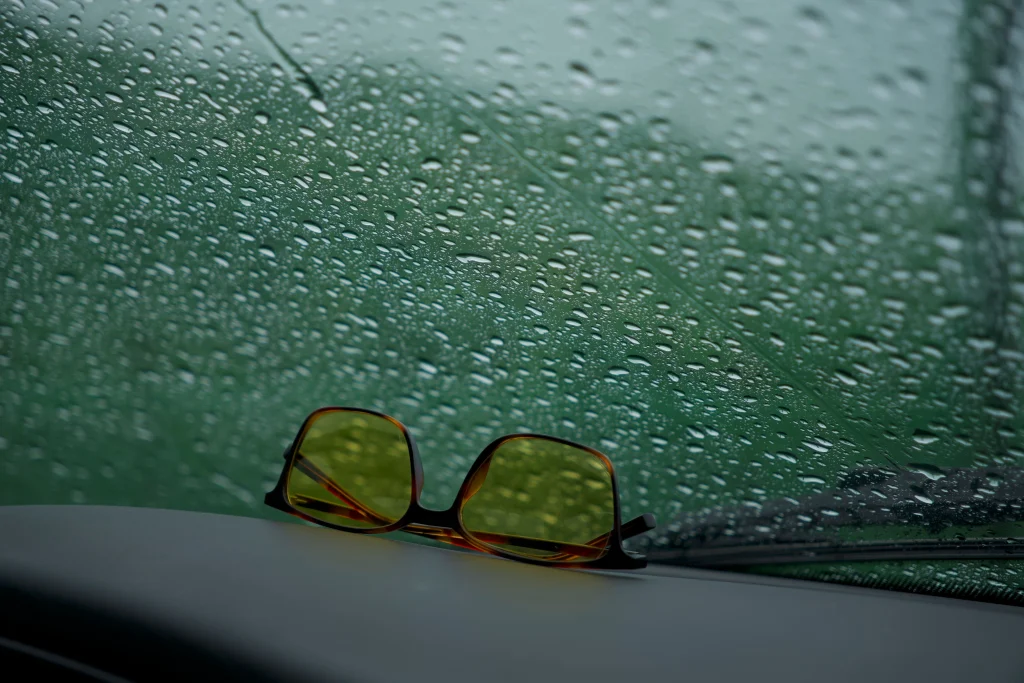 Quay vs Ray-Ban: Which Sunglasses Are Worth the Money? 2 Polarized sunglasses on a car dashboard with sun glare on the road ahead